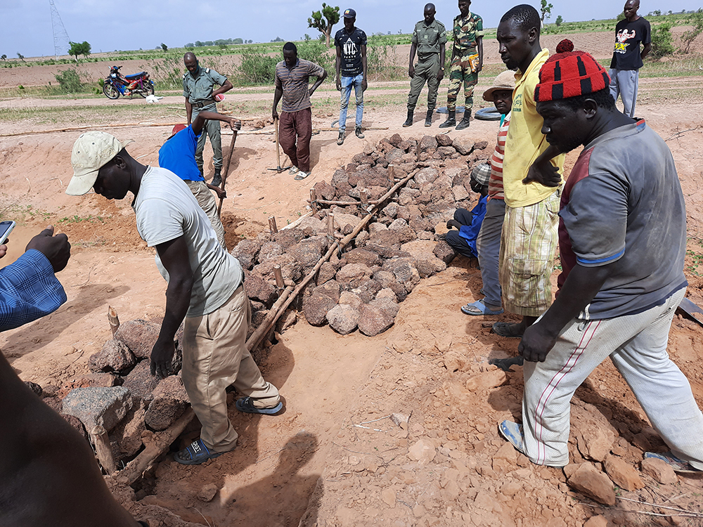 Les membres de la communauté aident à construire des digues de pierre le long des courbes de niveau. Photo prise par Matar Diaga Sarr.