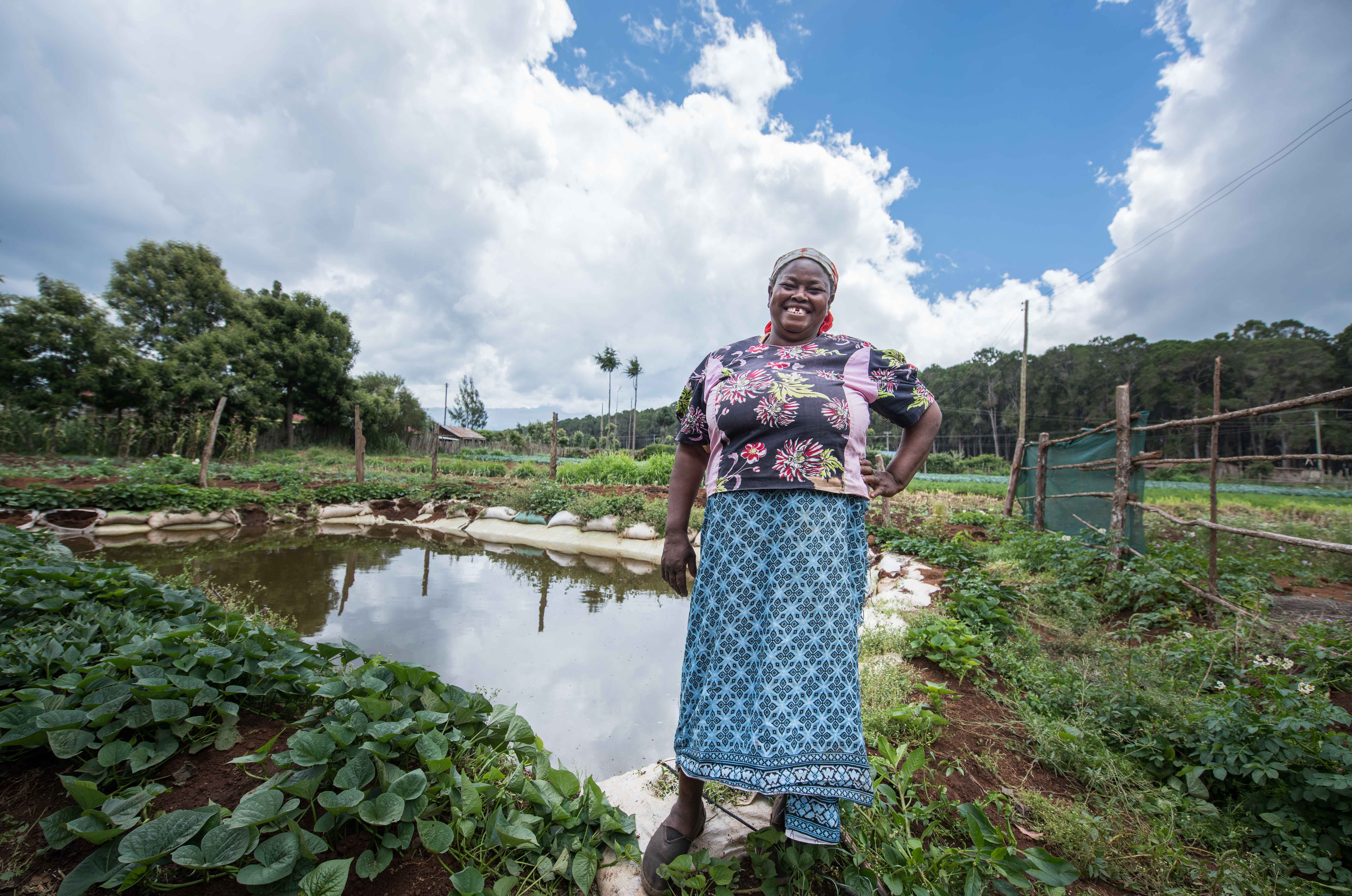 A farmer by her 50,000 liters water pan for growing vegetables in Nyeri County. Photo credit: Roshni Lodhia/TNC